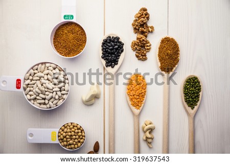 Spoons and cups of pulses and seeds on wooden table
