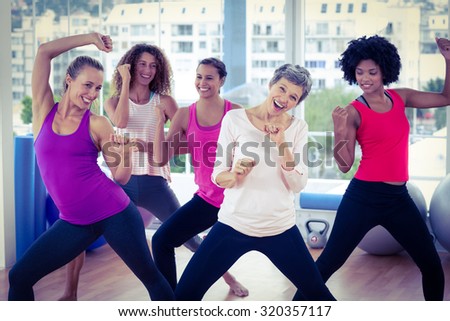 Portrait of happy women exercising with clasped hands in fitness studio