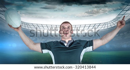 A rugby player gesturing victory against rugby stadium