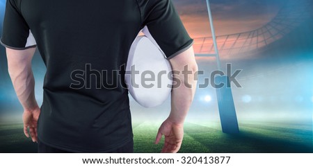 Rugby player holding a rugby ball against rugby stadium