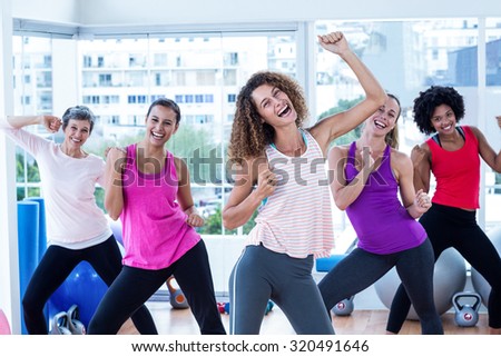 Portrait of women exercising with clasped hands in fitness studio