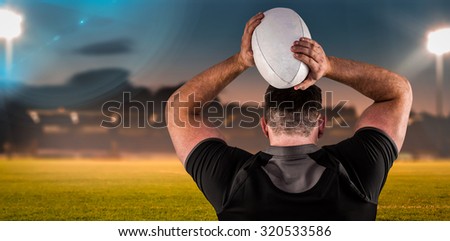 Tough rugby player throwing ball against pitch