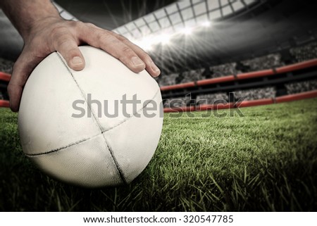 A rugby player posing a rugby ball against rugby stadium
