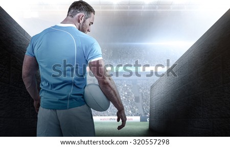 Rugby player standing with ball against rugby stadium
