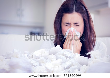 Brunette sneezing in a tissue against used tissues