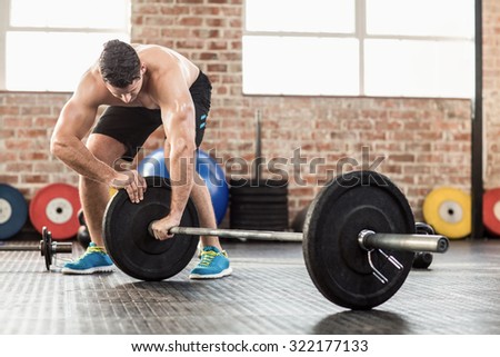 Muscular man set up his barbell weight in crossfit gym