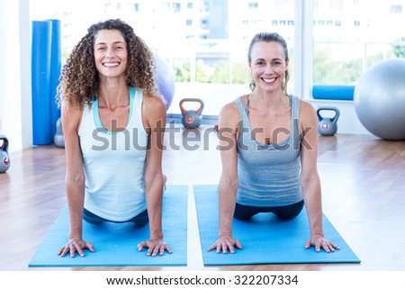 Portrait of cheerful women doing cobra pose in fitness studio