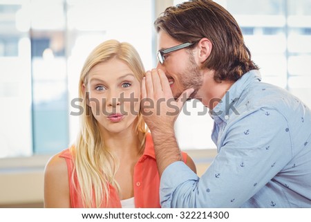 Businesswoman listening to rumor which male colleague is whispering into her ear