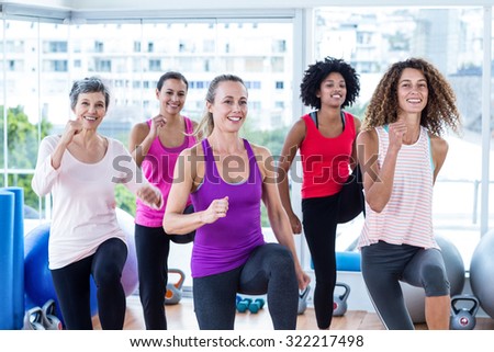 Portrait of smiling women exercising with clasped hands in fitness studio