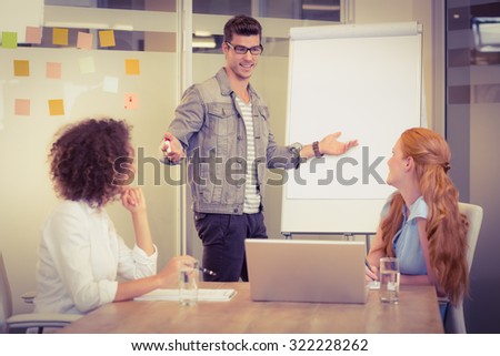 Businessman explaining female colleagues using whiteboard in office during meeting