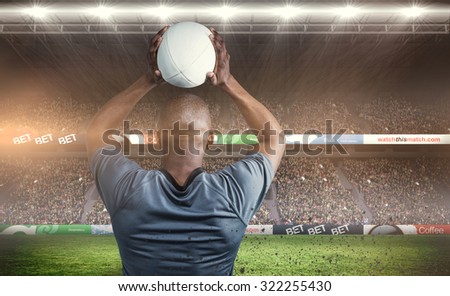Rear view of athlete throwing rugby ball against rugby fans in arena