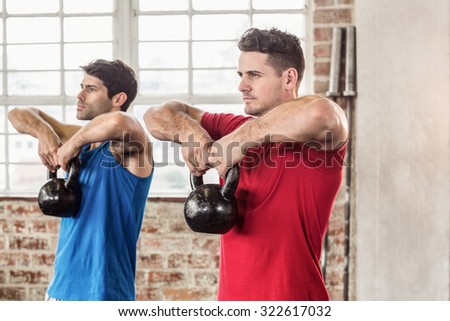 Muscular men lifting a kettle bell in crossfit gym