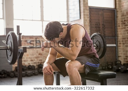 Tired man sitting on the bench at the gym
