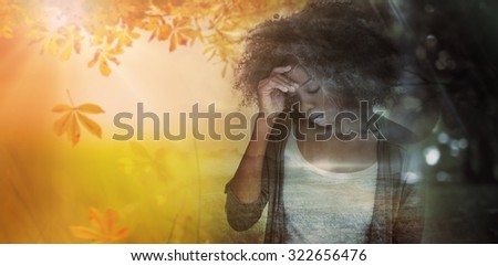 Sad woman holding her forehead with her hand against autumn scene