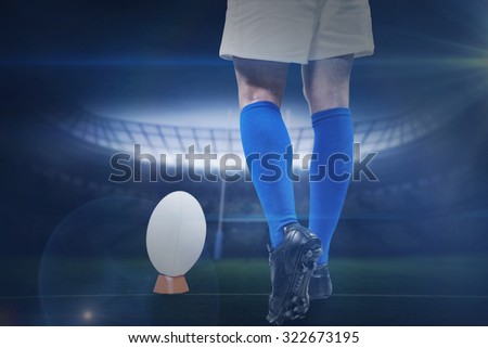 Low section of rugby player going to kick the ball against rugby stadium