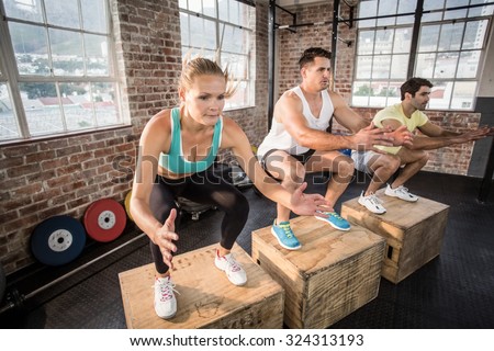 Fit people doing jump box in crossfit gym