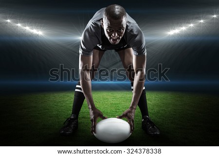 Portrait of sportsman holding ball while playing rugby against rugby stadium