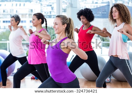 Women exercising with clasped hands and stretching in fitness studio