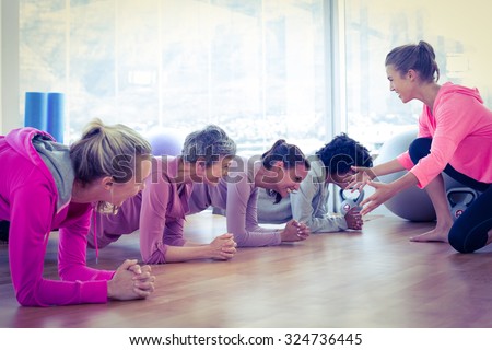 Smiling group of women exercising on floor in fitness studio