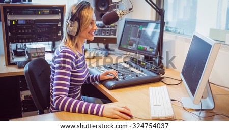 Side view of female radio host broadcasting through microphone in studio