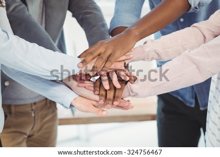 Mid section of business team putting their hands together at office