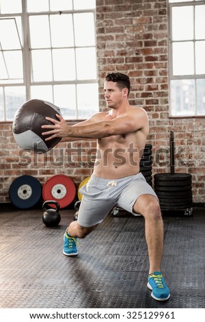 Muscular man exercising with medicine ball at the gym