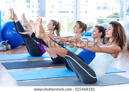Fit women in fitness studio doing boat pose on exercise mat