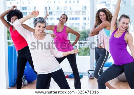 Cheerful women exercising with arms raised in fitness studio