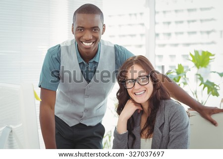 Portrait of happy business professionals at computer desk in office