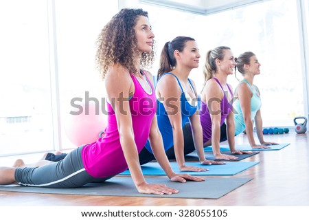 Side view of women doing cobra pose in fitness studio
