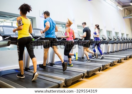 Fit people jogging on treadmills at the gym