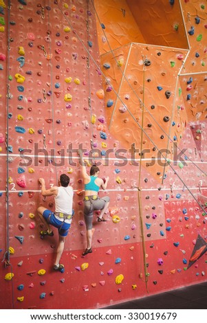Couple climbing up rock wall at the gym