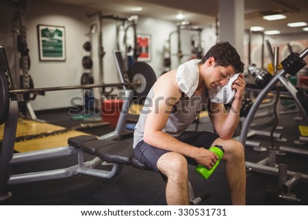 Fit man taking a break from working out at the gym