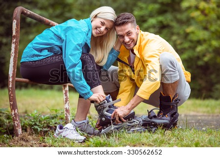 Happy couple putting on roller blades in the countryside