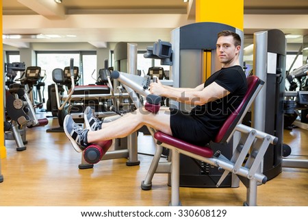 Fit man using weights machine for legs at the gym