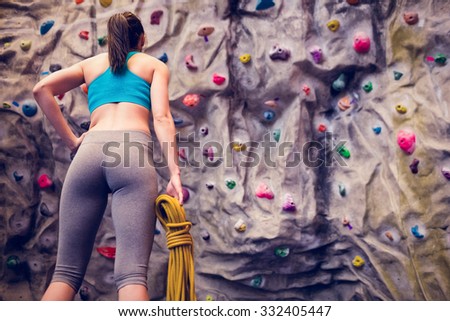 Fit woman looking up at rock climbing wall at the gym