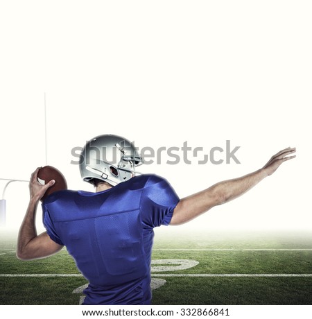 Rear view of American football player throwing ball against american football posts