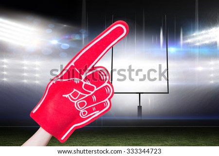 American football player holding supporter foam hand against american football arena