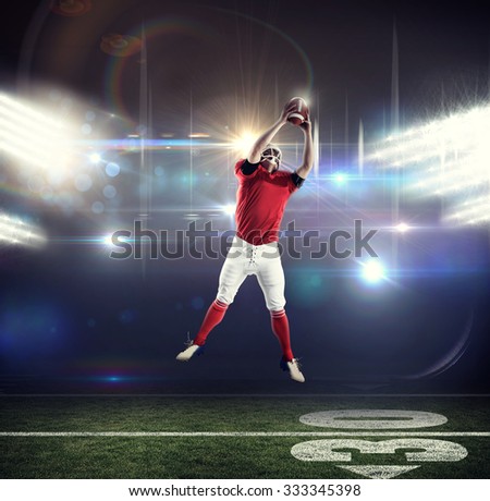 American football player catching football against american football arena