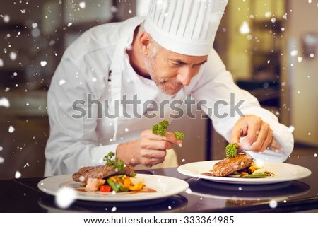 Snow against concentrated male chef garnishing food in kitchen