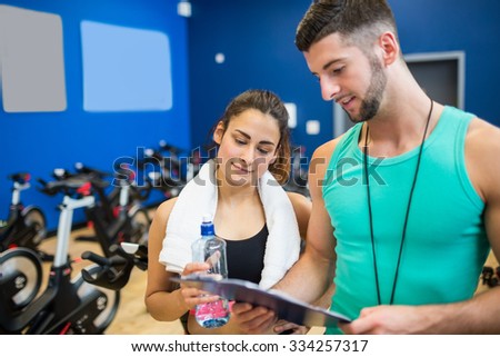 Trainer and athlete reading workout plan at the gym