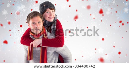 Man giving girlfriend piggy back against snowflake pattern