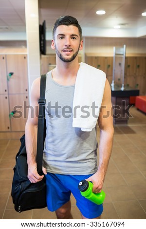 Smiling man about to go to the gym in the gym locker room