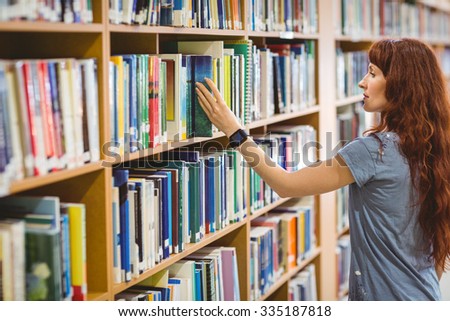 Mature student picking book in library wearing smart watch at the university
