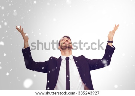Businessman cheering with hands raised against snow
