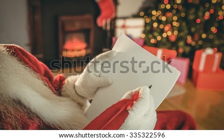 Santa claus writing list with a quill at home in the living room