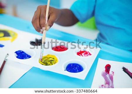 Happy kid enjoying arts and crafts painting at their desk