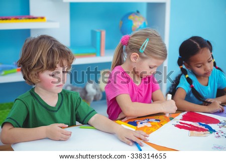 Happy kids all drawing pictures at their desk