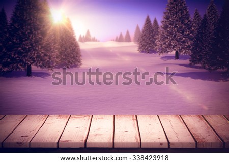Wooden table against snowy landscape with fir trees