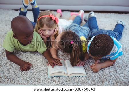 Happy kids reading a book together on the floor